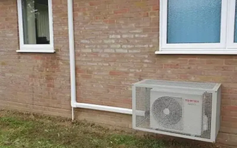 Fujitsu outdoor unit with a protective guard on a brick wall (Crawley Medical Centre case study)