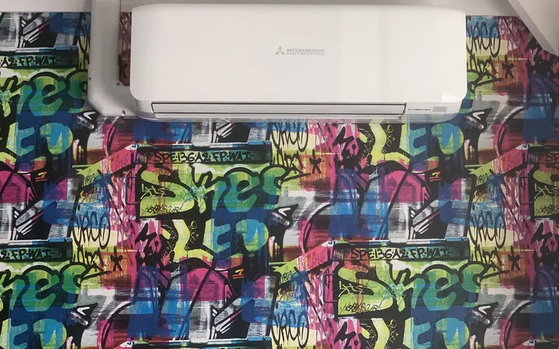 Mitsubishi wall-mounted indoor unit on a graffiti-print wall