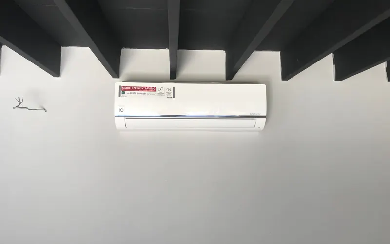 Wall-mounted LG split air conditioning unit installed in a room with exposed ceiling beams