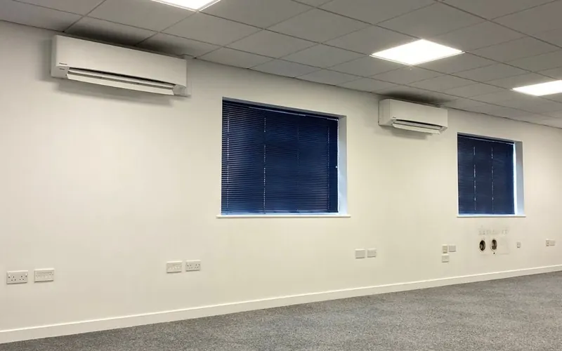 Two wall-mounted indoor units in a bright, newly finished office room