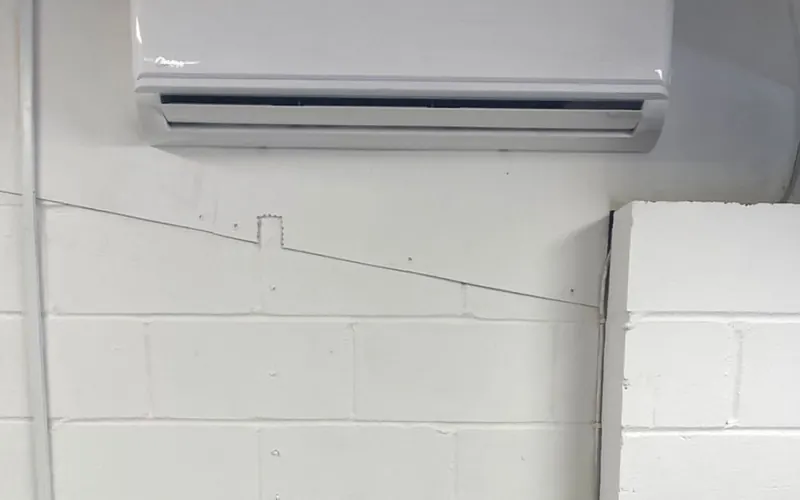 Wall-mounted indoor unit on a white painted block wall