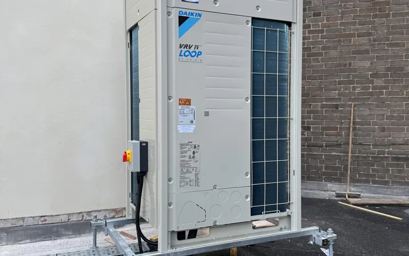 Daikin outdoor unit on a raised plinth against a rendered wall