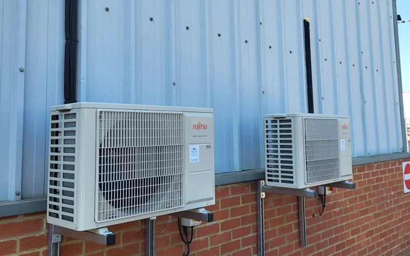Fujitsu outdoor air conditioning units mounted on a brick and cladding wall