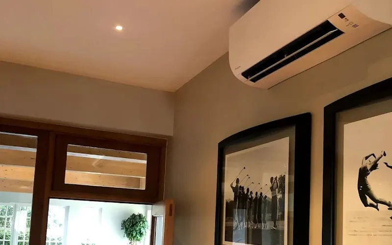 Wall mounted air conditioner installed in house above picture frames